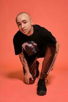 Studio shot of a young tattoed bald man posing against a pink background. 90s style. photo