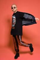 Studio shot of a young tattoed bald man posing against a pink background. 90s style. photo