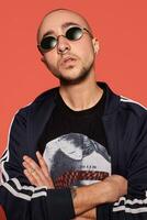 Studio shot of a young tattoed bald man posing against a pink background. 90s style. photo