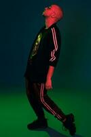 Studio shot of a young tattoed bald man posing against a colorful background. 90s style. photo