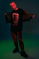 Studio shot of a young tattoed bald man posing against a colorful background. 90s style. photo