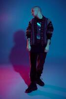 Studio shot of a young tattoed bald man posing against a colorful background. 90s style. photo