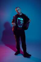 Studio shot of a young tattoed bald man posing against a colorful background. 90s style. photo