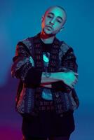 Studio shot of a young tattoed bald man posing against a colorful background. 90s style. photo