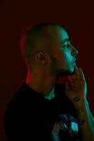 Studio shot of a young tattoed bald man posing against a red background. 90s style. photo