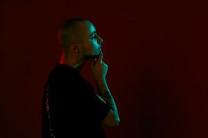 Studio shot of a young tattoed bald man posing against a red background. 90s style. photo