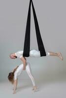 Beautiful girl and an athletic man in a white sport suits are performing an acrobatic elements in a studio. photo