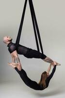 hermosa niña y un atlético hombre en un negro deporte trajes son ejecutando un acrobático elementos en un estudio. foto