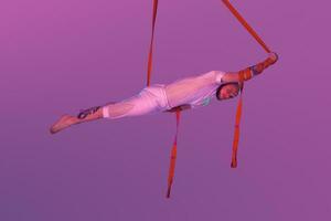 Athletic man in a white sport suit is performing an acrobatic elements in a studio. photo