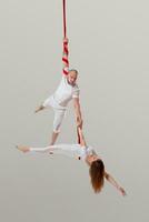 hermosa niña y un atlético hombre en un blanco deporte trajes son ejecutando un acrobático elementos en un estudio. foto