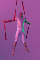 Athletic man in a white sport suit is performing an acrobatic elements in a studio. photo