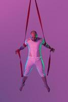 Athletic man in a white sport suit is performing an acrobatic elements in a studio. photo