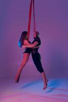 hermosa niña y un atlético hombre en un negro deporte trajes son ejecutando un acrobático elementos en un estudio. foto