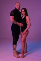 Athletic gymnasts in a black sport suits are posing in a studio. photo