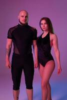 Athletic gymnasts in a black sport suits are posing in a studio. photo