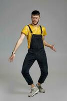 Full-length portrait of a funny guy dancing in studio on a gray background. photo