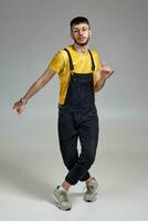 Full-length portrait of a funny guy dancing in studio on a gray background. photo