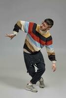 Full-length portrait of a funny guy dancing in studio on a gray background. photo