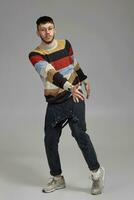 Full-length portrait of a funny guy dancing in studio on a gray background. photo