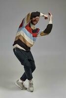 Full-length portrait of a funny guy dancing in studio on a gray background. photo
