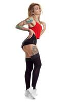 Sexy blond twerk woman with tattoed body and long curly hair is posing in studio. photo