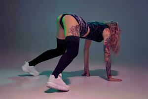 Sexy blond woman with tattoed body and long curly hair is dancing twerk in studio. photo