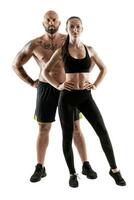 Athletic man in black shorts and sneakers with brunette woman in leggings and top posing isolated on white background. Fitness couple, gym concept. photo