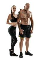 atlético hombre en negro pantalones cortos y zapatillas con morena mujer en polainas y parte superior posando aislado en blanco antecedentes. aptitud pareja, gimnasio concepto. foto