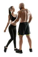 Athletic man in black shorts and sneakers with brunette woman in leggings and top posing isolated on white background. Fitness couple, gym concept. photo