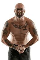 Athletic bald, tattooed man in black shorts is posing isolated on white background. Close-up portrait. photo