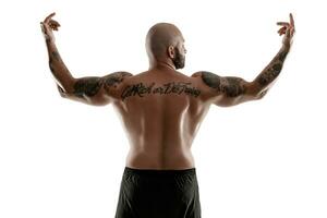 Athletic bald, tattooed man in black shorts is posing isolated on white background. Close-up portrait. photo