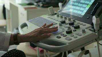 servië, Belgrado - september 13, 2023. de vrouw dokter hand- voert een medisch inspectie, gebruik makend van een echografie scanner. klem. dichtbij omhoog van een echografie machine en een dokter hand- werken Aan het. video