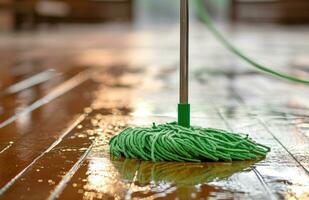 ai generado limpiar piso en un de madera piso con verde fregona foto