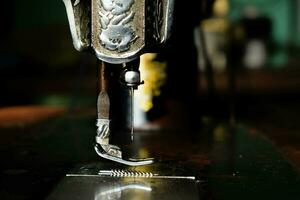 Close up sewing machine with needle on wood table, antique sewing machine with dust photo