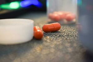 medical pill and bottle with mug or glas of water on table workspace photo