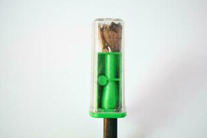 green pencil sharpener and dark green pencils on white background photo