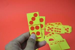 hand hold dominoes playing cards isolated red background, yellow red dominoes cards photo