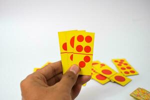 hand hold dominoes playing cards isolated white background, yellow red dominoes cards photo