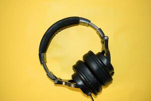 top view black headphone with cable on yellow background photo