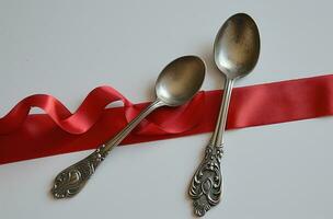 AI generated a silver spoon and fork are next to a red ribbon photo