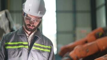 fabriek Mens ingenieur inspecteren Aan machine met slim tablet. arbeider werken Bij zwaar machine robot arm. kunstmatig intelligentie- concept. specialist arbeider werken Bij hoogte technologie industrie. video