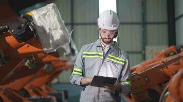 fabriek Mens ingenieur inspecteren Aan machine met slim tablet. arbeider werken Bij zwaar machine robot arm. kunstmatig intelligentie- concept. specialist arbeider werken Bij hoogte technologie industrie. video