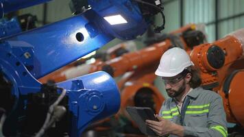 fabbrica uomo ingegnere ispezionando su macchina con inteligente tavoletta. lavoratore lavori a pesante macchina robot braccio. artificiale intelligenza concetto. specialista lavoratore Lavorando a altezza tecnologia industria. video