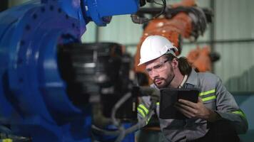 fabriek Mens ingenieur inspecteren Aan machine met slim tablet. arbeider werken Bij zwaar machine robot arm. kunstmatig intelligentie- concept. specialist arbeider werken Bij hoogte technologie industrie. video