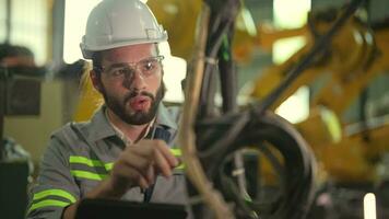 fabriek Mens ingenieur inspecteren Aan machine met slim tablet. arbeider werken Bij zwaar machine robot arm. kunstmatig intelligentie- concept. specialist arbeider werken Bij hoogte technologie industrie. video