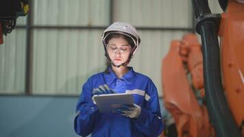 Factory engineer woman inspecting on machine with smart tablet. woman walking at machine robot arm. The welding machine with a remote system in an industrial factory. Artificial intelligence concept. video