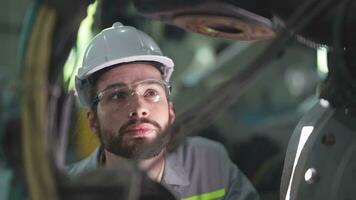 fabbrica uomo ingegnere ispezionando su macchina con inteligente tavoletta. lavoratore lavori a pesante macchina robot braccio. artificiale intelligenza concetto. specialista lavoratore Lavorando a altezza tecnologia industria. video