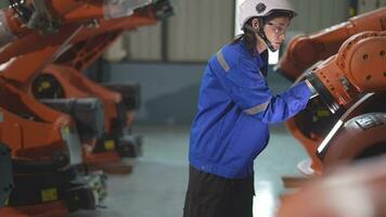 fabriek ingenieur vrouw inspecteren Aan machine met slim tablet. vrouw wandelen Bij machine robot arm. de lassen machine met een afgelegen systeem in een industrieel fabriek. kunstmatig intelligentie- concept. video