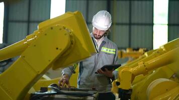 fabbrica uomo ingegnere ispezionando su macchina con inteligente tavoletta. lavoratore lavori a pesante macchina robot braccio. artificiale intelligenza concetto. specialista lavoratore Lavorando a altezza tecnologia industria. video