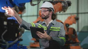 fabriek Mens ingenieur inspecteren Aan machine met slim tablet. arbeider werken Bij zwaar machine robot arm. kunstmatig intelligentie- concept. specialist arbeider werken Bij hoogte technologie industrie. video